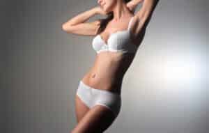 Photo of a slender woman wearing a white bra and underwear set after undergoing body contouring surgery