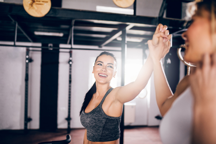 Two athletic women in the gym give each other a high five