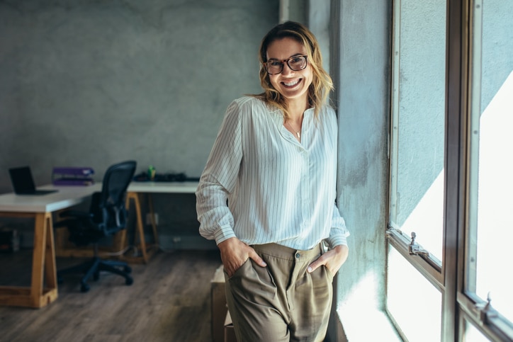 A woman with her hand in her pockets standing in an office.