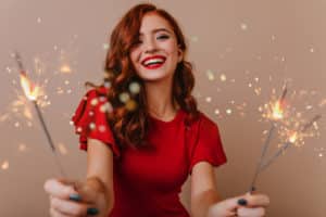 red haired girl holding sparklers and laughing in new year.