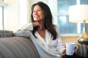 hispanic woman sitting on a sofa holding a cup of coffee