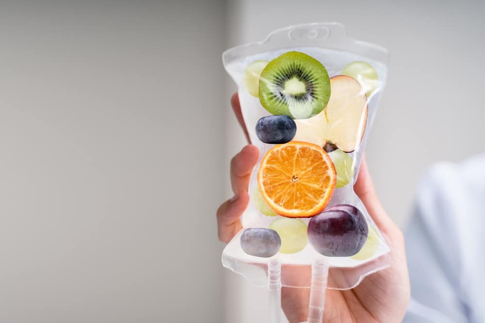 Photo shows a representation of IV therapy with fruits and nutrients inside a bag of saline attached to an IV drip.