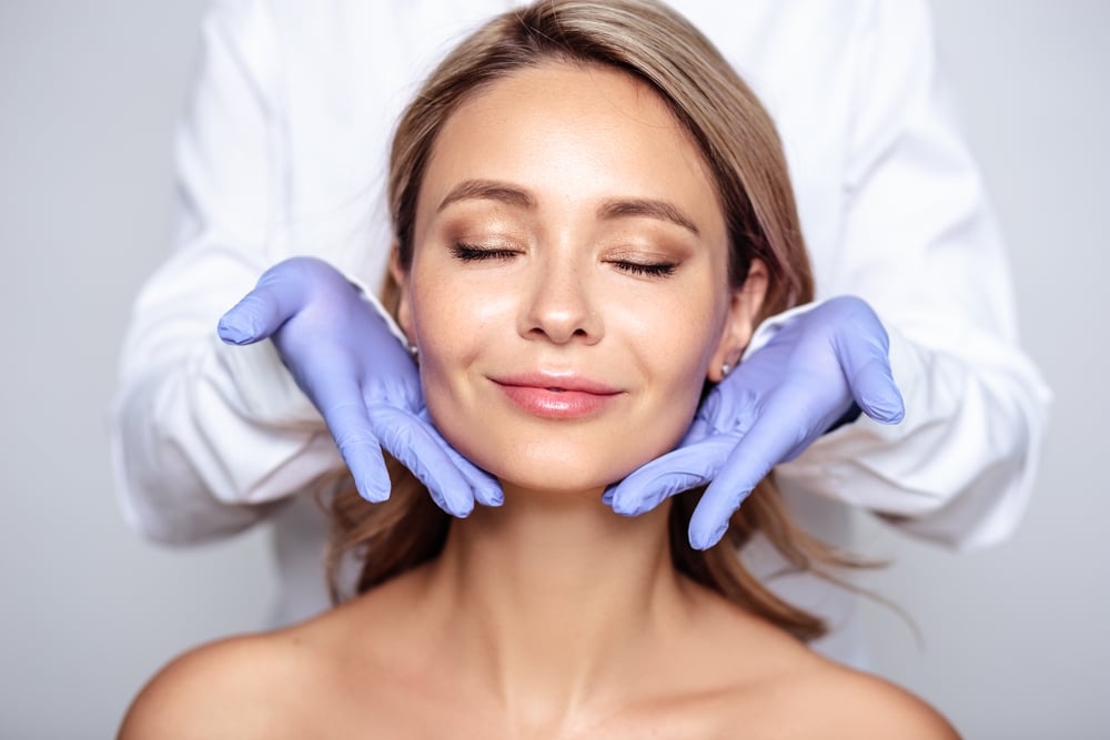 Woman smiling with eyes closed next to gloved hands after Moxi laser treatment