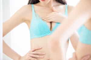 Woman in bra touching her breast after explant surgery in Dallas, TX
